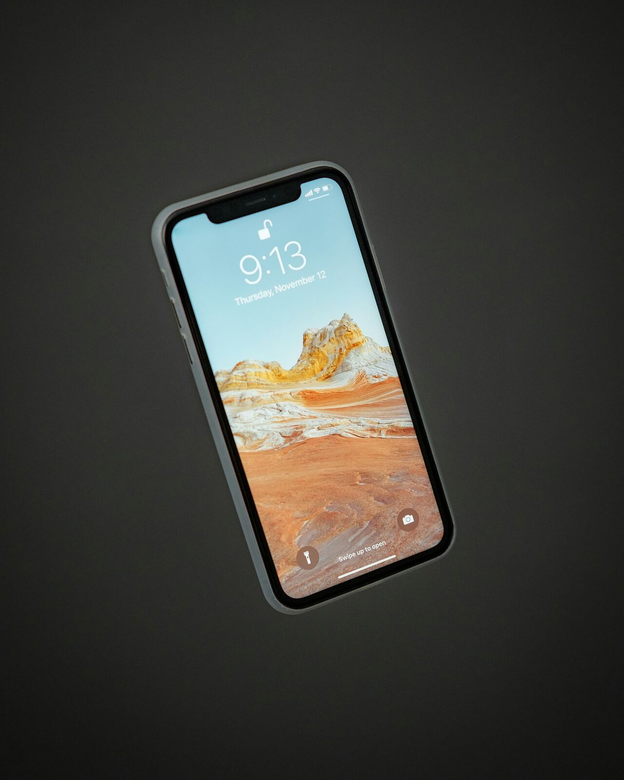 A close up of a phone screen showing app icons being deleted, held in soft daylight.
